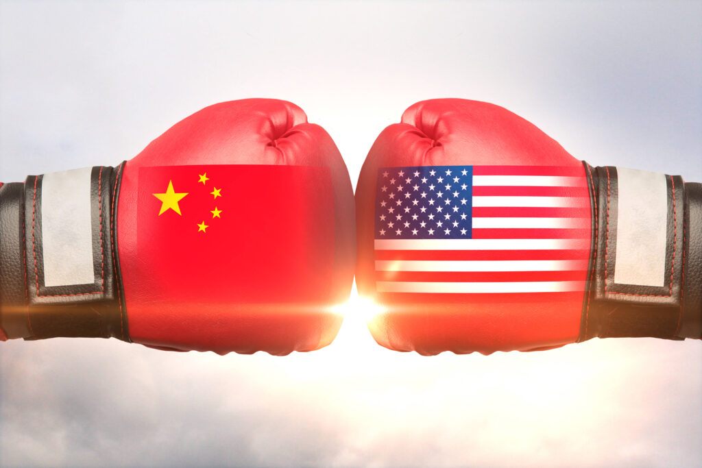 Boxing gloves touching, one glove has the Chinese flag, the other the American flag